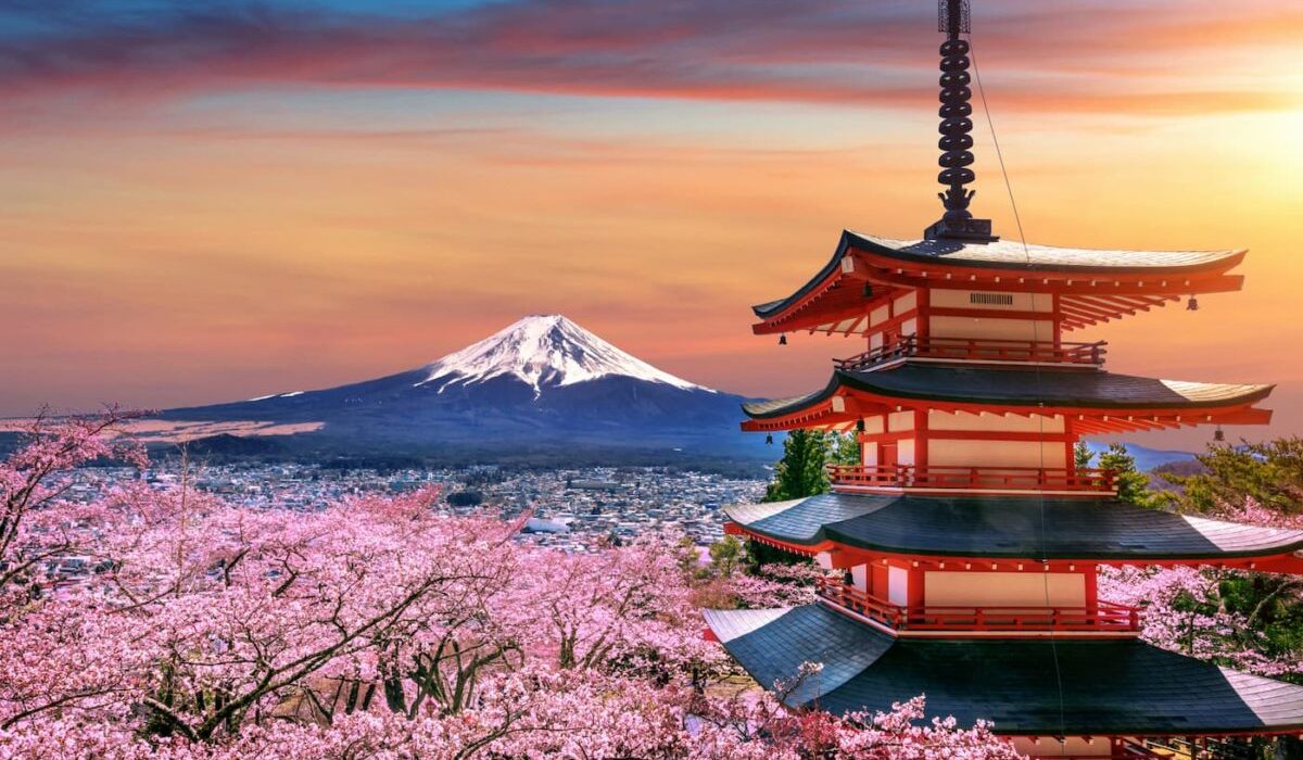 Una alta torre japonesa contra el fondo de una megalópolis y montañas.